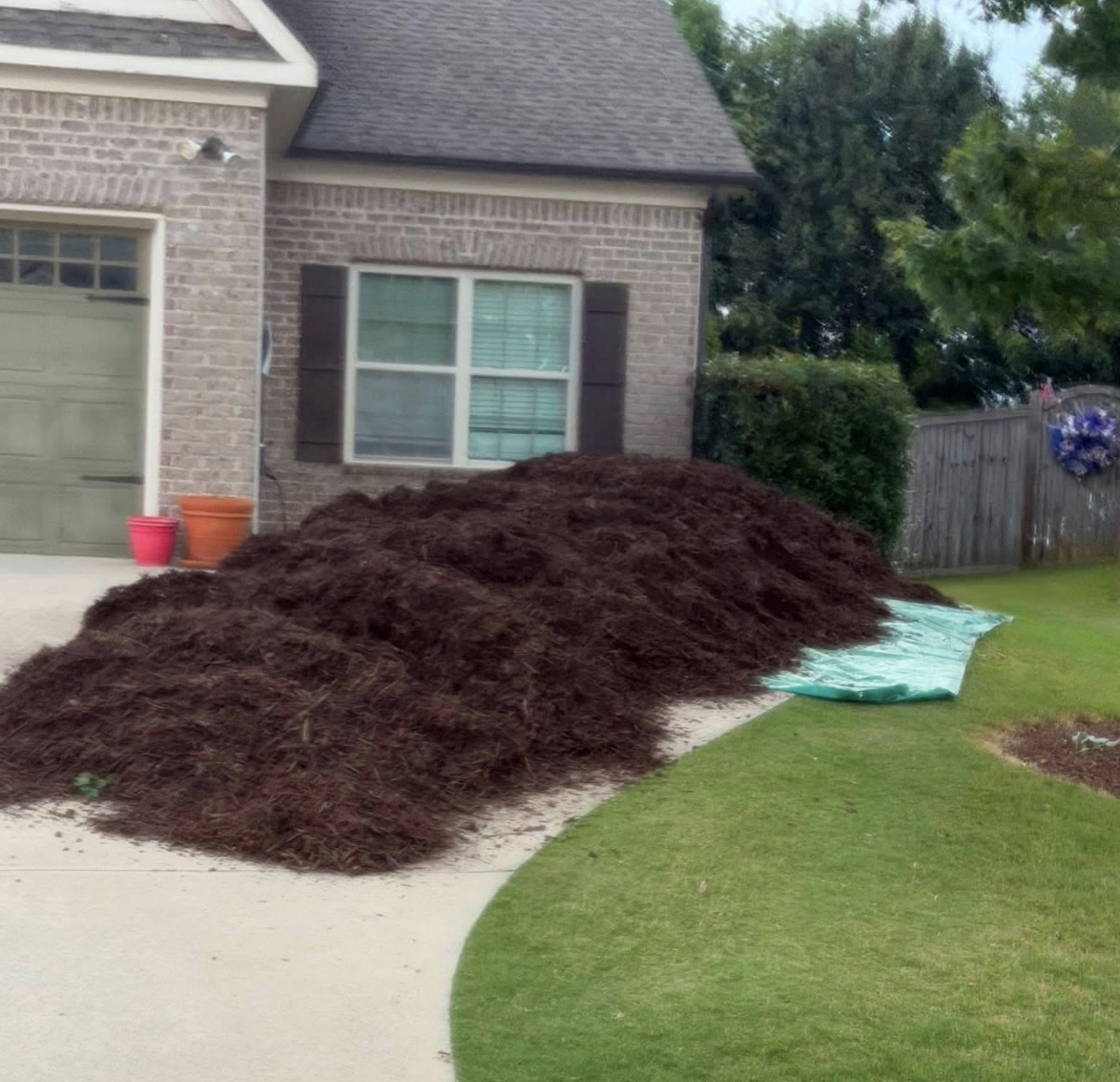 Large brown mulch pile delivered in a driveway