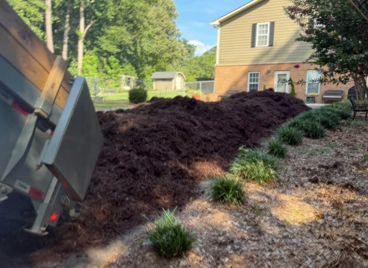 Dump trailer unloading mulch at a customer property